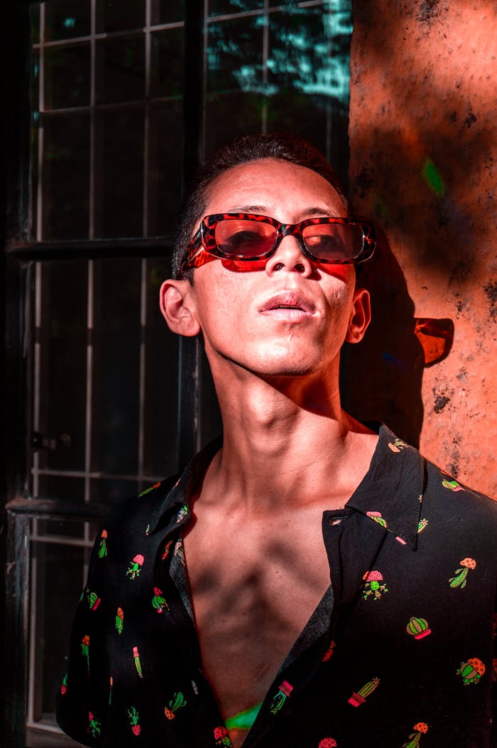 services-01 Fashionable young man in sunglasses against a rustic wall, sunlit in São Paulo.